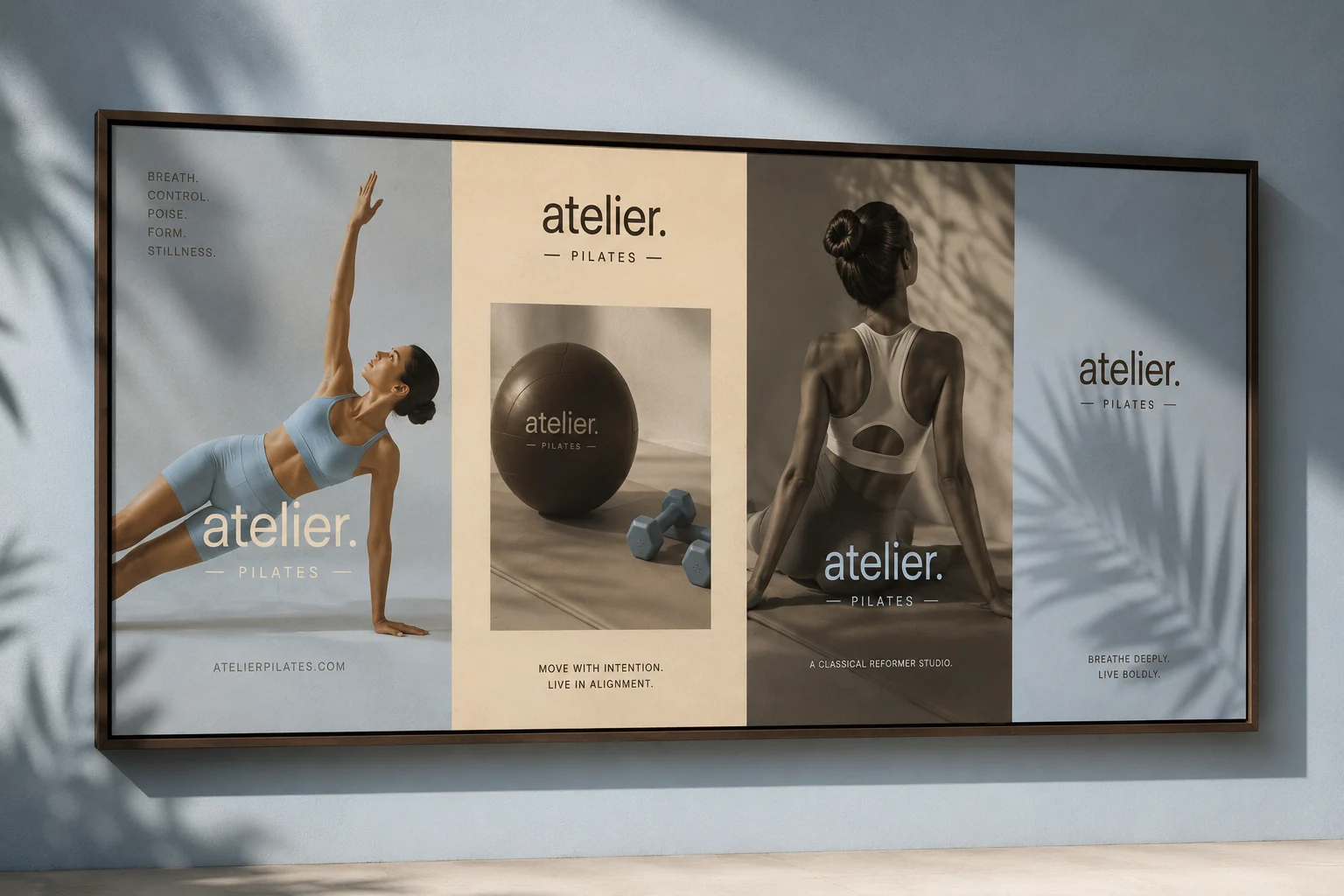 Four-panel Atelier campaign poster framed on a pale blue wall in palm-dappled light
